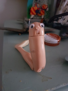 Picture of broken off 12” action figure leg with eyes stuck on it so it looks like a creature.