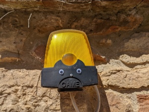 Picture of an amber warning light for an automatic gate with plastic googly eyes on it to make it look like an irritated face.