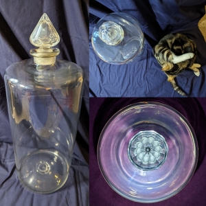 Three pictures of a huge glass bottle with a cut glass lid from above, side and with cat for size.
